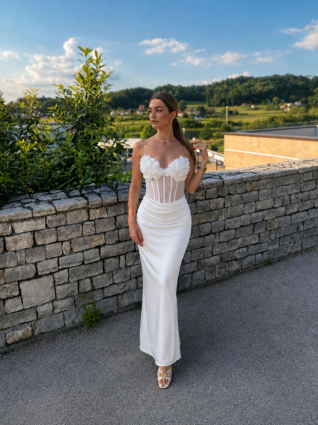 Elegantna bijela maxi haljina s korzetom i cvjetnim detaljima.